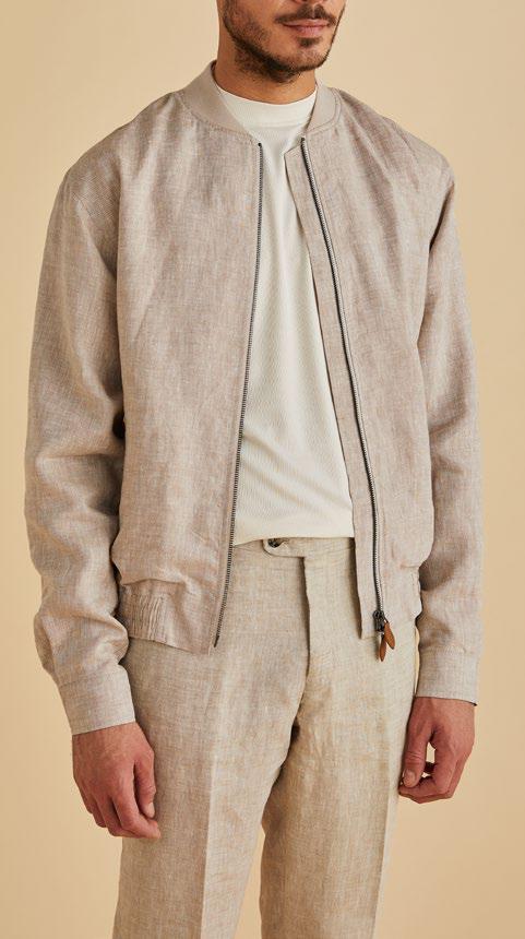 A person is pictured in an Inserch Linen Bomber Jacket Suit JS660-00006 Oatmeal, styled over a white shirt and slim fit pants, standing against a beige backdrop. The jacket from Inserch is zipped halfway, enhancing the chic, monochromatic appeal.