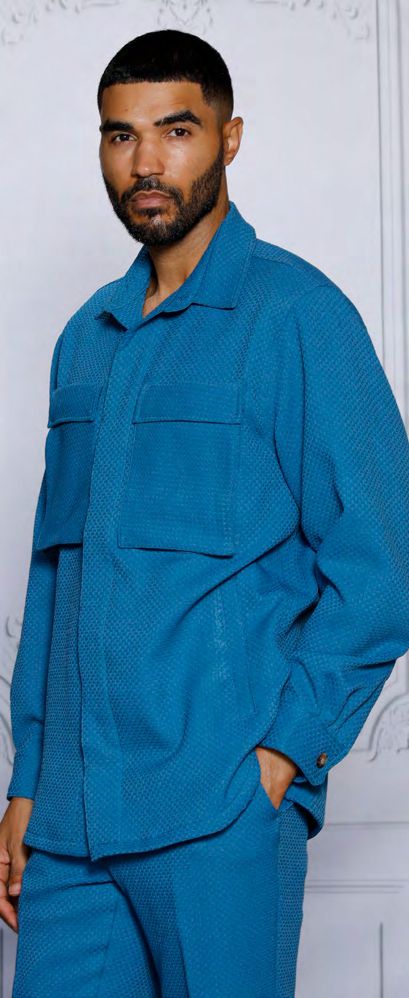 A man with short dark hair and a beard is wearing the INSOMNIA ROBERTO 2PC Teal Leisure Suit by Insomnia, standing against a light-colored background.