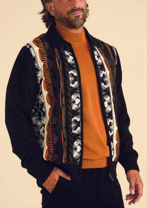 A person wears the Inserch 3D Intarsia Full Zip Sweater SW907-01 in black, which features a multicolored vertical stripe pattern, layered over an orange sweater.