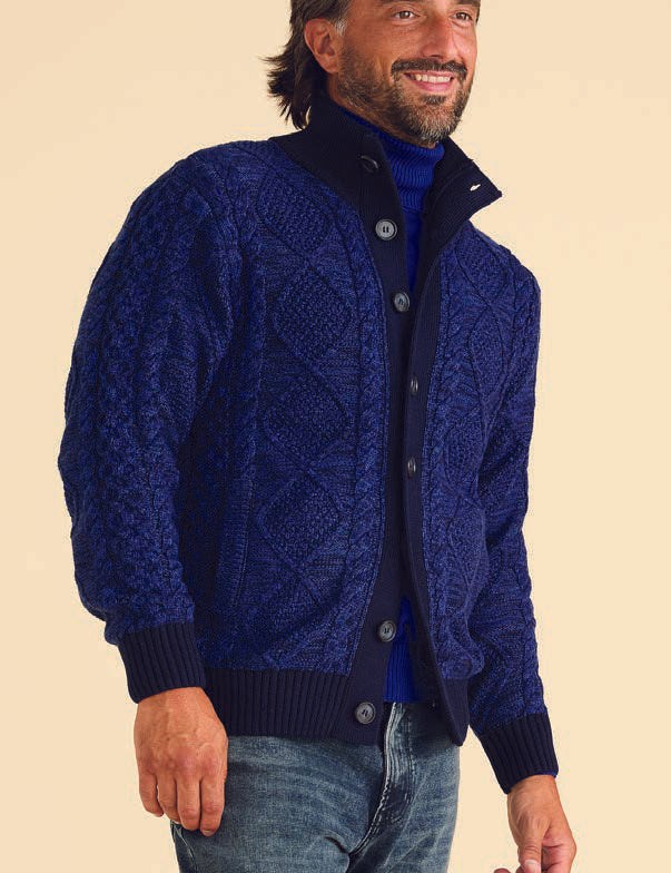 An individual wearing the Inserch Marled Cable Cardigan SW905-11 in navy blue over a dark shirt stands against a beige background.