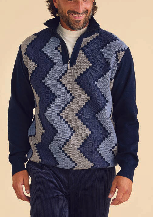 A person wearing the Inserch Zig-Zag Half Zip Sweater SW613-11 Navy Blue with a white shirt underneath and dark pants smiles while standing against a beige background.