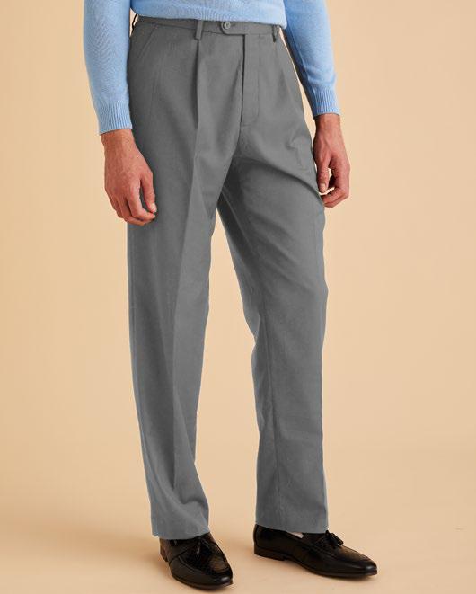 A person wearing Inserch's One Pleat Pants P0599S-00033 Grey and a light blue sweater stands against a beige background.