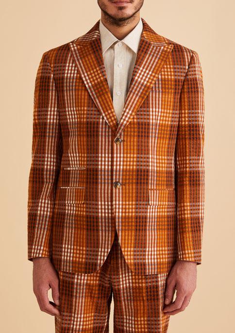 A man wearing a brown plaid suit and a white shirt, complemented by the Inserch Seersucker Gingham Suit BL272-00027 Aztec blazer, stands against a beige background.