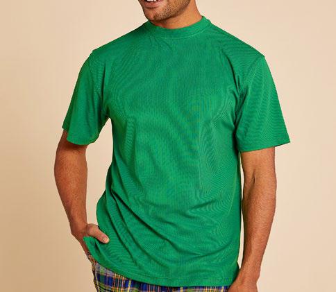 An individual wearing the Inserch Short Sleeve Crewneck Rib T-Shirt T299-200 in an emerald shade and plaid pants poses against a beige backdrop, smiling with one hand in their pocket.