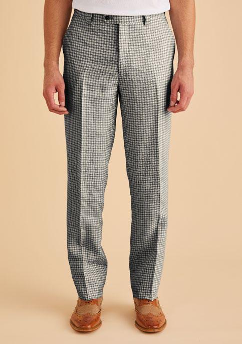 A person wearing Inserch Linen Houndstooth Pants in black and white, paired with brown shoes, stands against a beige background.