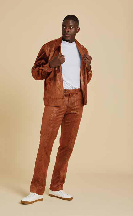 A person wearing the Inserch Sueded Snake Skin Embossed Jacket, style JS268-104 in Cognac, paired with a white t-shirt underneath, displays its subtle printed lining. The regular fit of this Inserch piece enhances its sleek appearance against the beige background.