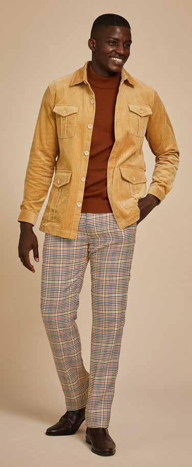 A person dressed in the Inserch 4-Pocket Cord Jacket BL267-09 Khaki, a modern corduroy tan jacket made of 100% cotton, paired with matching pants and a white turtleneck, stands against a plain background.