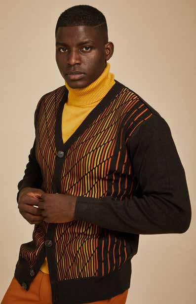 A man wearing the Inserch Intarsia Panel Cardigan SW904-24 Chocolate, which features a geometric intarsia pattern with multicolored diagonal stripes, paired with a mustard turtleneck and jeans.