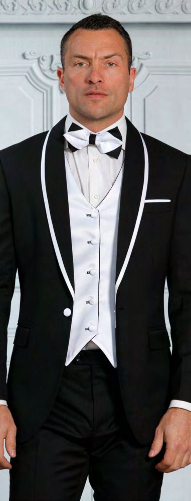 A man wearing the INSOMNIA SUNSET 3PC Slim Fit Black White Tuxedo Suit from Insomnia, paired with a white dress shirt and a reversible vest, completes his look with a crisp white bow tie.