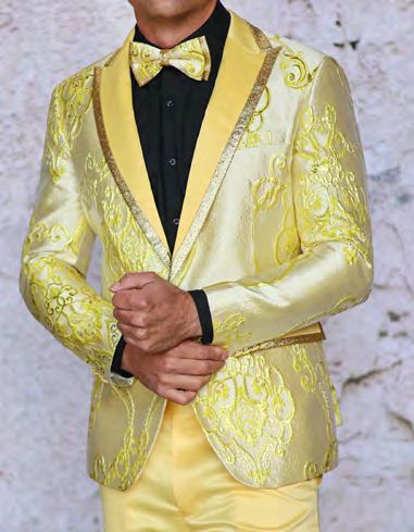 An individual confidently wears the INSOMNIA MZS-538 Tailored Fit Yellow Woven Sport Coat by Insomnia, adorned with intricate designs and completed with a coordinating bow tie over an elegant black shirt.