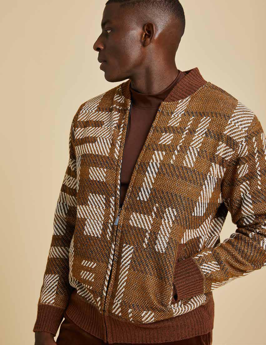 A man wears the Inserch Geometric Full Zip Baseball Knit Jacket SW609-27 Aztec over a black turtleneck, paired with brown pants.