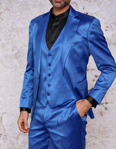 A person wearing the INSOMNIA CLASSICO 3PC Tailored Fit Satin Spandex Royal Suit from Insomnia, paired with a black shirt, stands against a textured background.