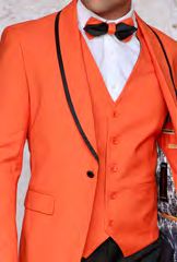 A person wears the INSOMNIA SUNSET 3PC Slim Fit Orange Tuxedo Suit by Insomnia, combined with a black bow tie and a crisp white shirt, exuding elegance with the added flair of a reversible vest.