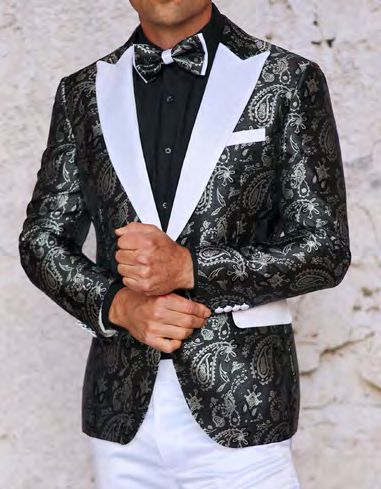 A person wearing the INSOMNIA MZS-551 Slim Fit Black White Woven Sport Coat by Insomnia, featuring a paisley pattern, white lapels, and a pocket square, stands against a light background, paired with a black shirt, bow tie, and white pants.