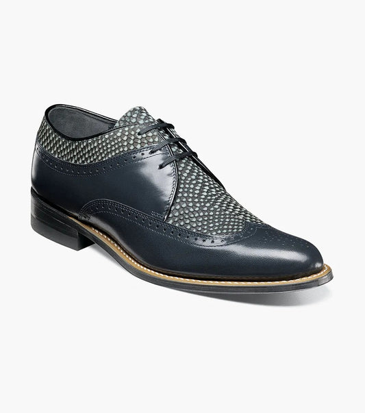 The Stacy Adams DAYTON Python Print Wingtip Oxford in navy is a sophisticated shoe, showcasing textured paneling and made from Kidskin leather. It includes sleek black laces and a polished wooden sole.