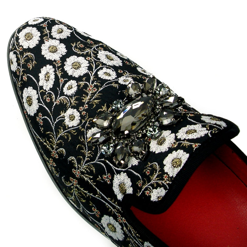 The FI-7386 Black Flowers Slip-on by Fiesso features ornate white floral embroidery and a decorative jewel on top. With a luxurious red interior lining, cushioned insole, and black sole, this stylish slip-on from Fiesso by Aurelio Garcia combines comfort with elegance effortlessly.