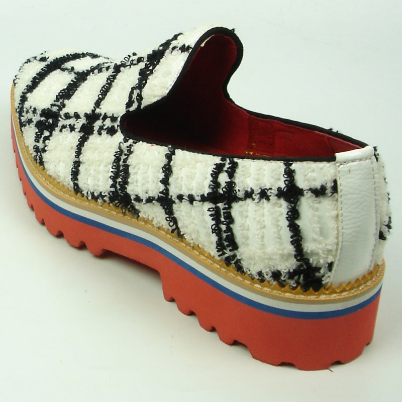 Featuring a black and white plaid pattern, the FI-7452 White Slip-On by Fiesso highlights a leather upper and vibrant red interior. The layered sole showcases red, blue, white, and rubber brown hues with a chunky tread, perfectly embodying the distinctive style of Fiesso by Aurelio Garcia.