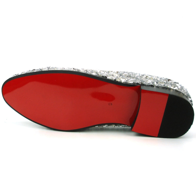 A single white slip-on shoe from the Fiesso by Aurelio Garcia collection, featuring a sleek design adorned with shiny beads, a black sole, and a luxurious red interior lining. Its textured crystals add a glamorous touch to the overall aesthetic.