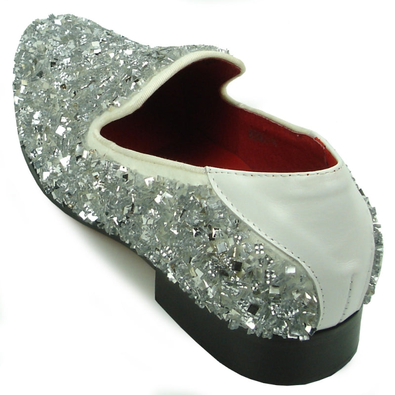 A single white slip-on shoe from the Fiesso by Aurelio Garcia collection, featuring a sleek design adorned with shiny beads, a black sole, and a luxurious red interior lining. Its textured crystals add a glamorous touch to the overall aesthetic.