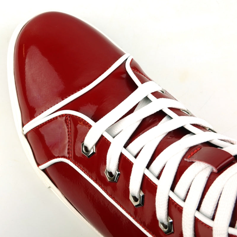 The FI-2416 Red Patent Leather High Top Sneaker by Fiesso is a striking piece with a glossy finish, adorned with white laces and trim, and featuring a white sole. It stands out against a plain background for an elegant and stylish look.