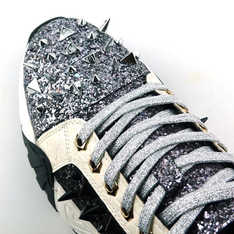 The FI-2406 Silver Black Encore by Fiesso is a sparkling men's casual sneaker featuring a glitter upper, black accents, metallic spikes on the front, white laces, a cushioned insole for enhanced comfort, and a thick black and white sole.