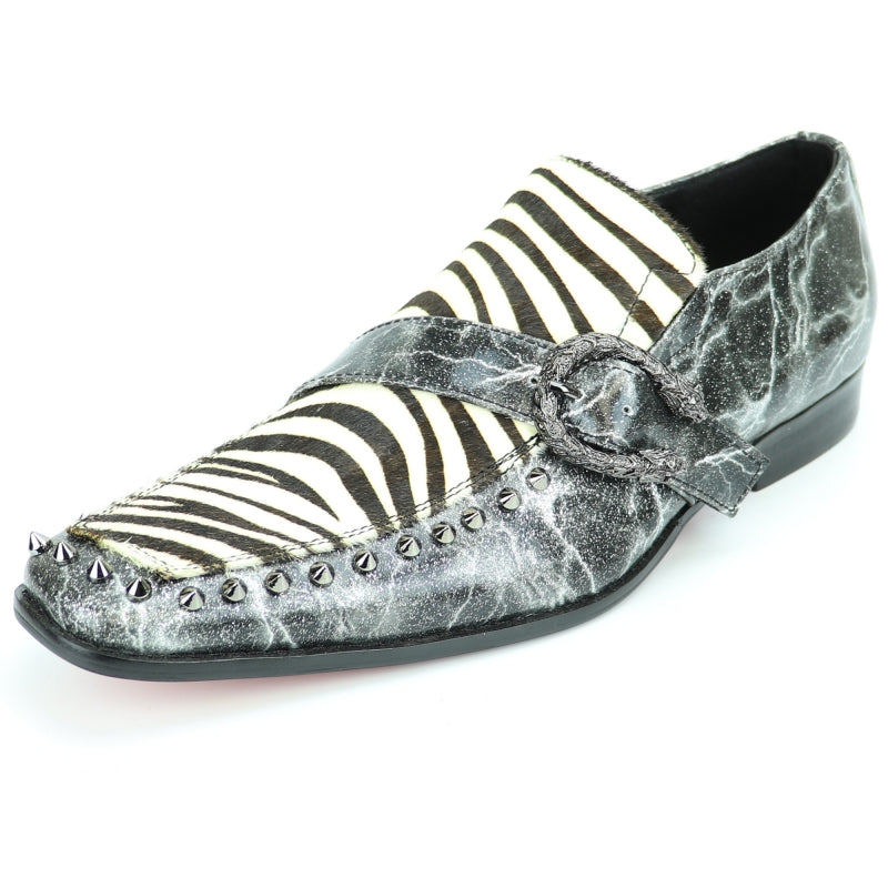 Introducing the Fiesso FI-7248 Black White Zebra Slip On by Aurelio Garcia, a fashion-forward shoe featuring a striking black and white zebra pattern. It is adorned with metallic spikes along the front and includes a textured strap with a buckle. The shoe's leather upper ensures both durability and style, while a cushioned insole provides added comfort.