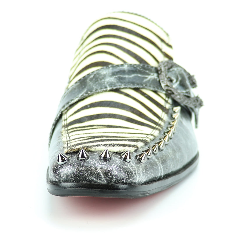 Introducing the Fiesso FI-7248 Black White Zebra Slip On by Aurelio Garcia, a fashion-forward shoe featuring a striking black and white zebra pattern. It is adorned with metallic spikes along the front and includes a textured strap with a buckle. The shoe's leather upper ensures both durability and style, while a cushioned insole provides added comfort.