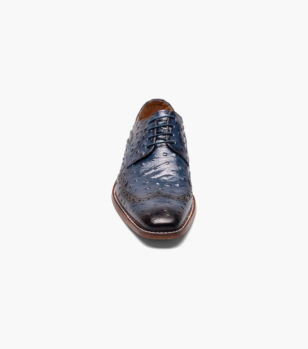 This blue Stacy Adams Gennaro Wingtip Oxford, featuring a textured ostrich quill print finish and a brown sole, elegantly captures the refined style associated with the Stacy Adams brand.