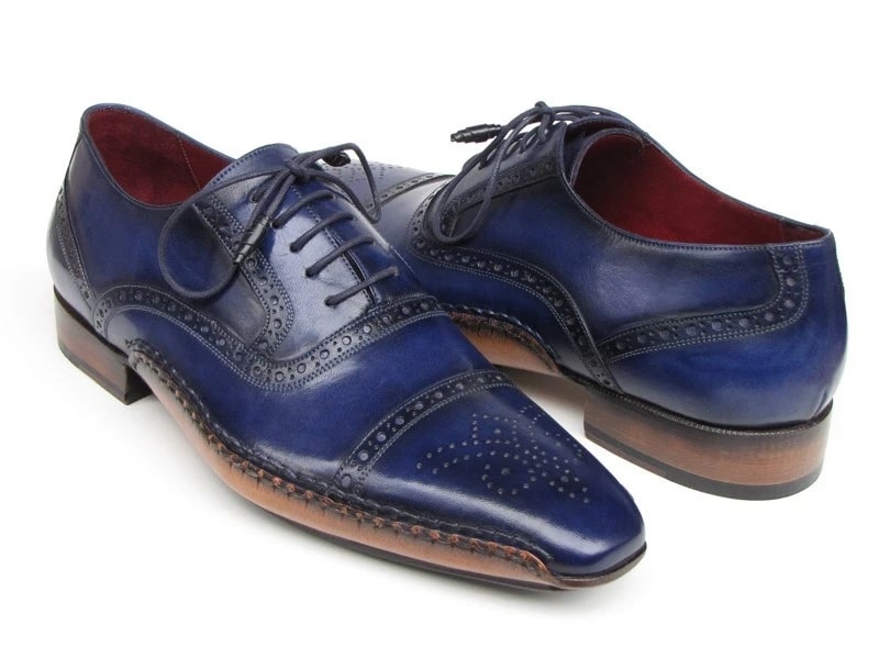 The Paul Parkman Captoe Navy Blue Hand Painted Oxfords - 5032-NAVY from Paul Parkman are a pair of men's handmade navy blue leather dress shoes. They feature decorative stitching, brown soles, laces, and a polished finish. These elegant oxfords exhibit the artistry of hand-painted leather for a sophisticated touch.