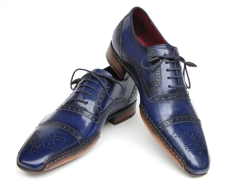 The Paul Parkman Captoe Navy Blue Hand Painted Oxfords - 5032-NAVY from Paul Parkman are a pair of men's handmade navy blue leather dress shoes. They feature decorative stitching, brown soles, laces, and a polished finish. These elegant oxfords exhibit the artistry of hand-painted leather for a sophisticated touch.