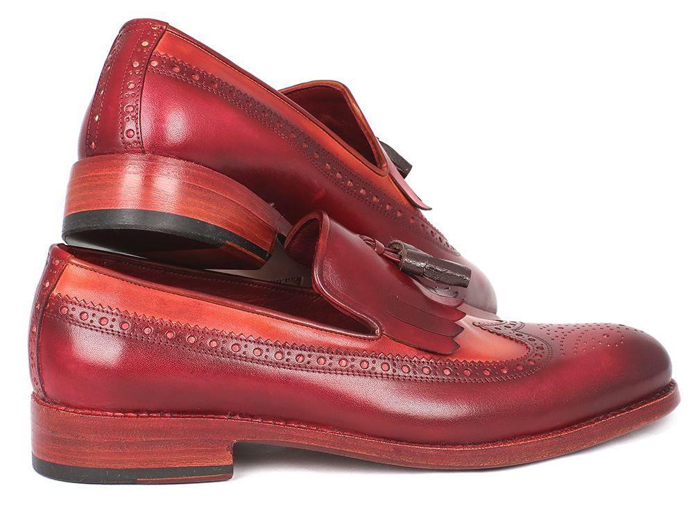 A pair of Paul Parkman Kiltie Tassel Loafers in Tobacco & Bordeaux, KT64CB, exquisitely crafted from handpainted calfskin with brown fringe details and intricate brogue patterns, arranged artfully with one shoe tilted against the other.