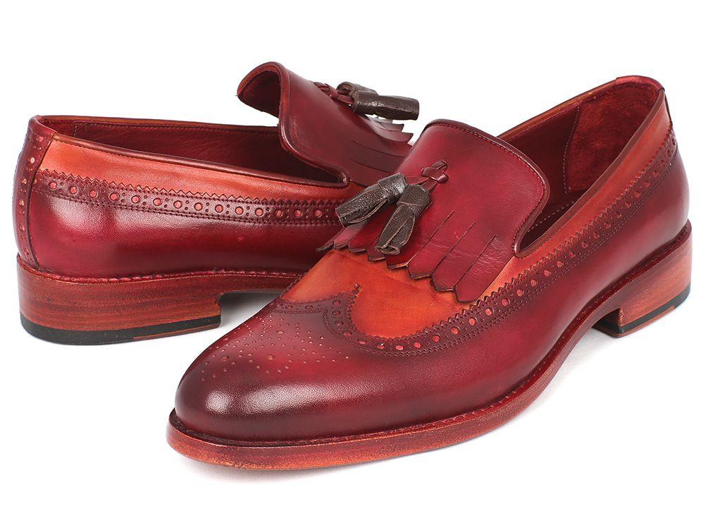 A pair of Paul Parkman Kiltie Tassel Loafers in Tobacco & Bordeaux, KT64CB, exquisitely crafted from handpainted calfskin with brown fringe details and intricate brogue patterns, arranged artfully with one shoe tilted against the other.