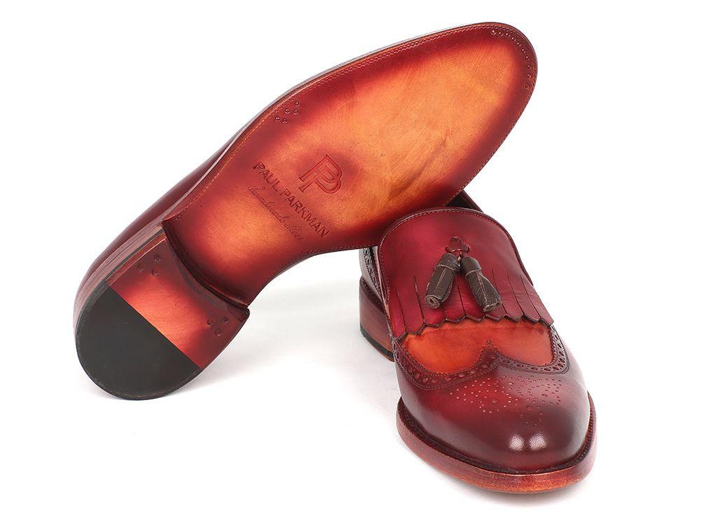 A pair of Paul Parkman Kiltie Tassel Loafers in Tobacco & Bordeaux, KT64CB, exquisitely crafted from handpainted calfskin with brown fringe details and intricate brogue patterns, arranged artfully with one shoe tilted against the other.