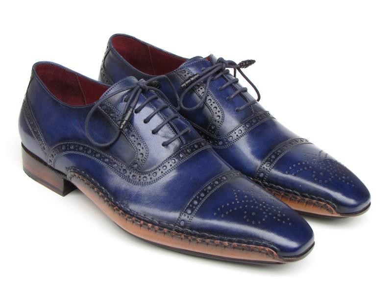 The Paul Parkman Captoe Navy Blue Hand Painted Oxfords - 5032-NAVY from Paul Parkman are a pair of men's handmade navy blue leather dress shoes. They feature decorative stitching, brown soles, laces, and a polished finish. These elegant oxfords exhibit the artistry of hand-painted leather for a sophisticated touch.