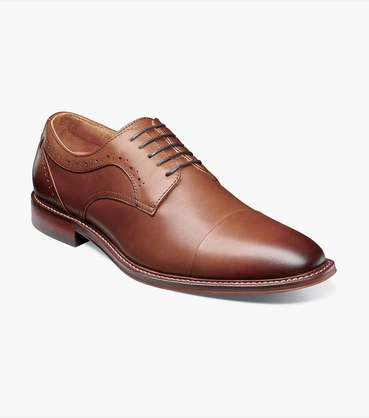 A lone chocolate-colored MADDOX Cap Toe Oxford dress shoe by STACY ADAMS, crafted from burnished leather with laces, showcasing a streamlined design and subtle decorative stitching, set against a light gray backdrop.