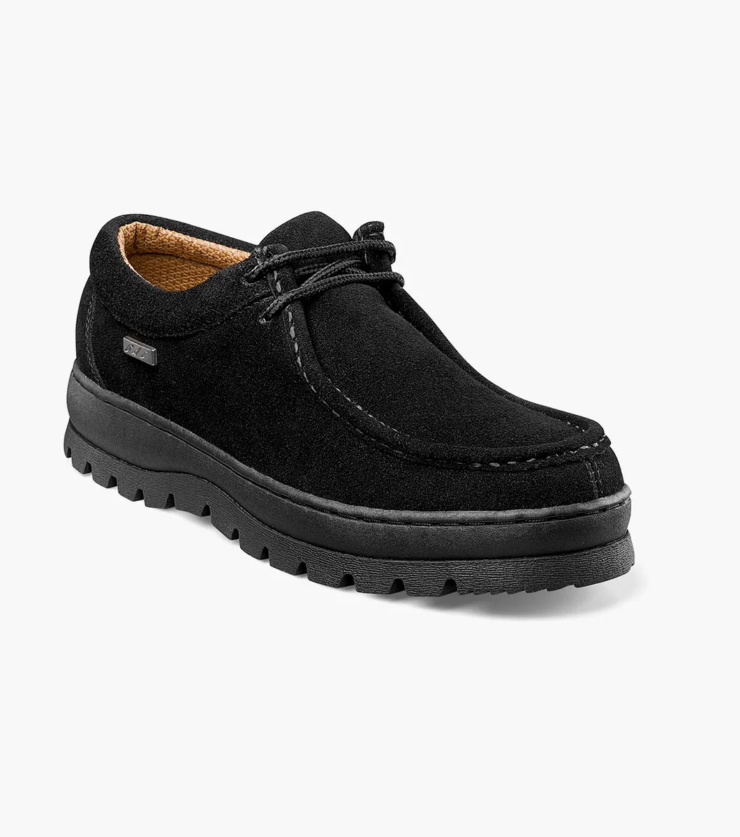 The Stacy Adams DETONATOR Moc Toe Chukka in black suede (63027-11) boasts soft suede material and laces, complemented by its oversized lug sole. Its thick, grooved rubber base enhances both style and comfort against a white background.