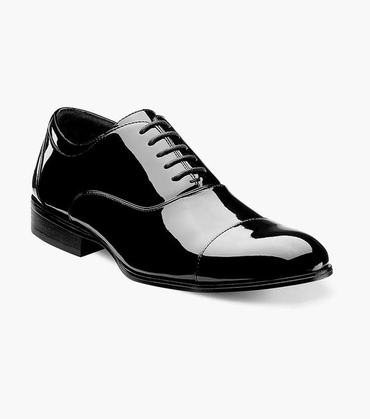 The Stacy Adams GALA Cap Toe Oxford dress shoe, model 24998-004, showcases a sleek design crafted from shiny black patent leather. It features a low heel and memory foam cushioning for enhanced comfort, elegantly displayed on a white background.