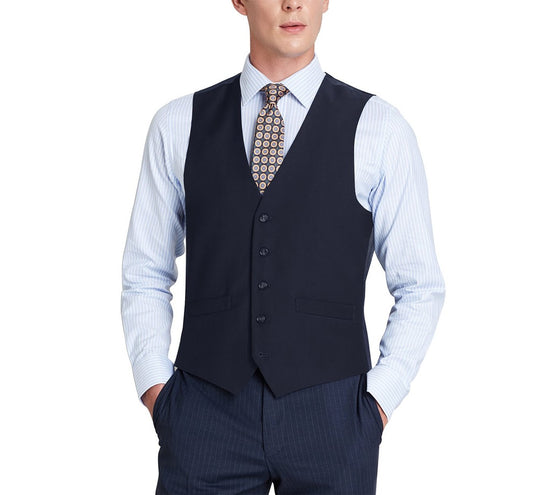 Man wearing a regular fit navy suit vest by Renoir called the Alessandro Vitello, paired with a classic fit blue pinstriped dress shirt and patterned tie, with hands in pockets.