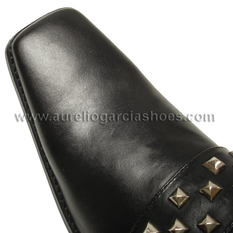 The FI-6563 Black Fiesso by Aurelio Garcia from the Fiesso brand is a slip-on leather shoe adorned with a band of silver studs across the top. It features a pointed toe and low heel, blending style and comfort with its cushioned insole.