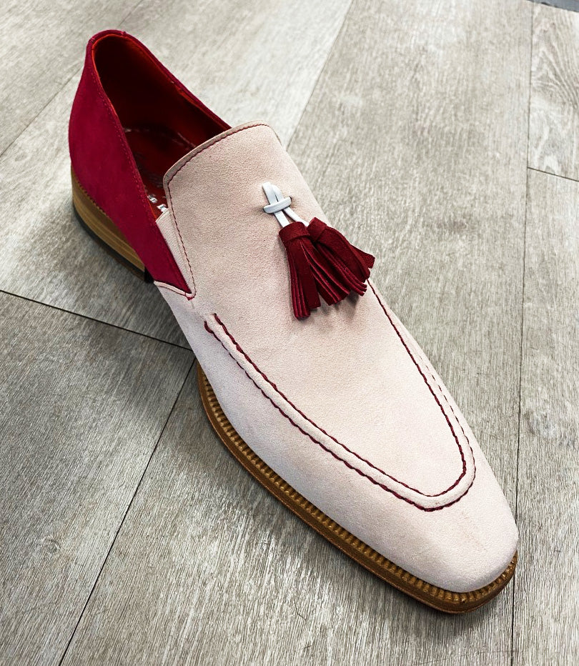 An Emilio Franco Suede Slip On FR289 in pink and fuchsia, adorned with a red tassel and decorative stitching, is placed on a wooden floor.