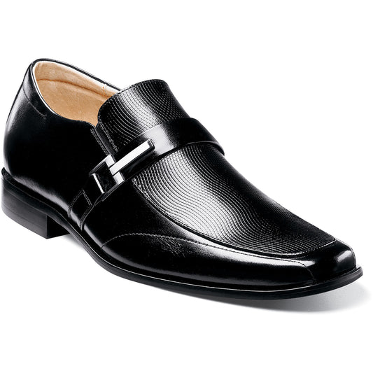 The Stacy Adams BEAU Moc Toe Loafer in black, model 24692-001, features a textured front with a decorative metal buckle and low heel. The design offers versatility with its supple leather upper and cushioned insole for added comfort, showcased elegantly from the side view.