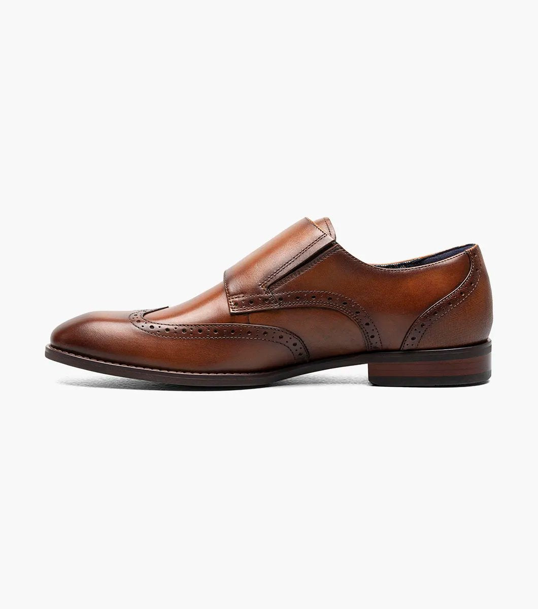 The Stacy Adams - KARSON Wingtip Double Monk Strap in cognac, model number 25570-221, is a shoe crafted with brown leather and features wingtip decorative perforations along with two side buckles, complemented by a RedZone footbed for exceptional comfort.