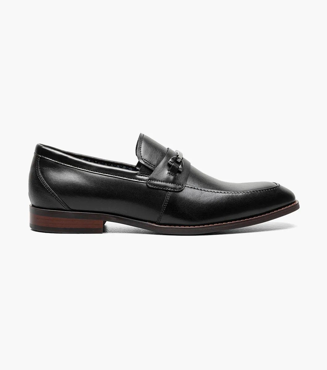 The Stacy Adams KAYLOR Moc Toe Bit Slip On in black (model 25572-001) is a sophisticated leather loafer from STACY ADAMS, highlighted by a sleek metal buckle, wooden heel, and premium leather upper. Perfectly set against a white background, it features the supportive RedZone footbed for exceptional comfort.