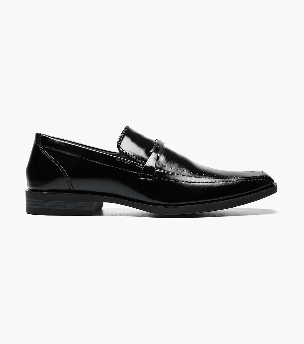 The Stacy Adams CADE Bike Toe Slip On in black, model 20126-001, is a stylish black leather loafer with a slip-on design. It features a gunmetal bit and a low heel, set against a plain white background.