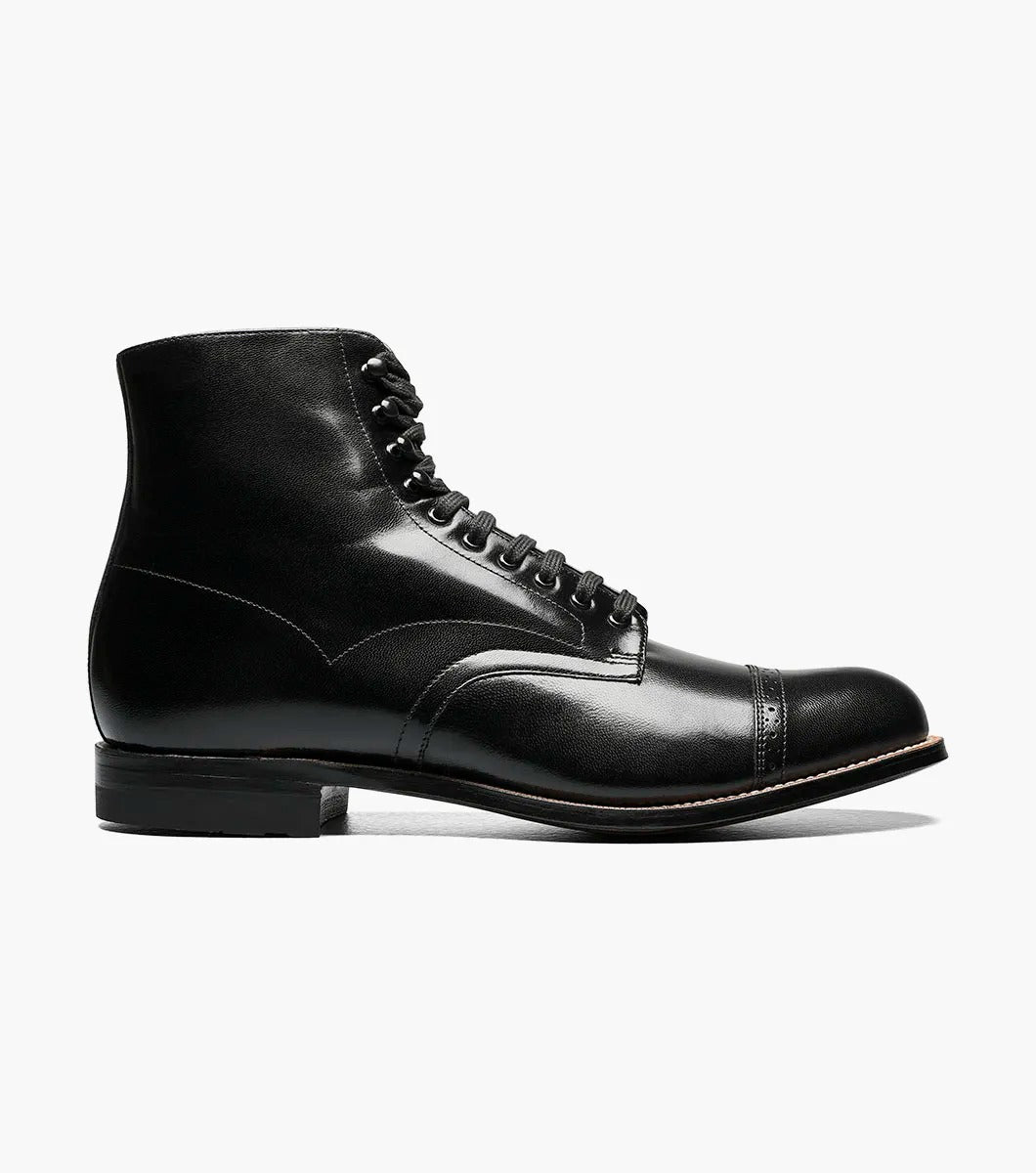 The Stacy Adams MADISON Cap Toe Boot, model 00015-01, is meticulously crafted from top-quality kidskin leather. It features a refined cap toe and a stacked heel. The durable Goodyear welt construction enhances the longevity of this sophisticated black leather boot with laces, attractively set against a white background.