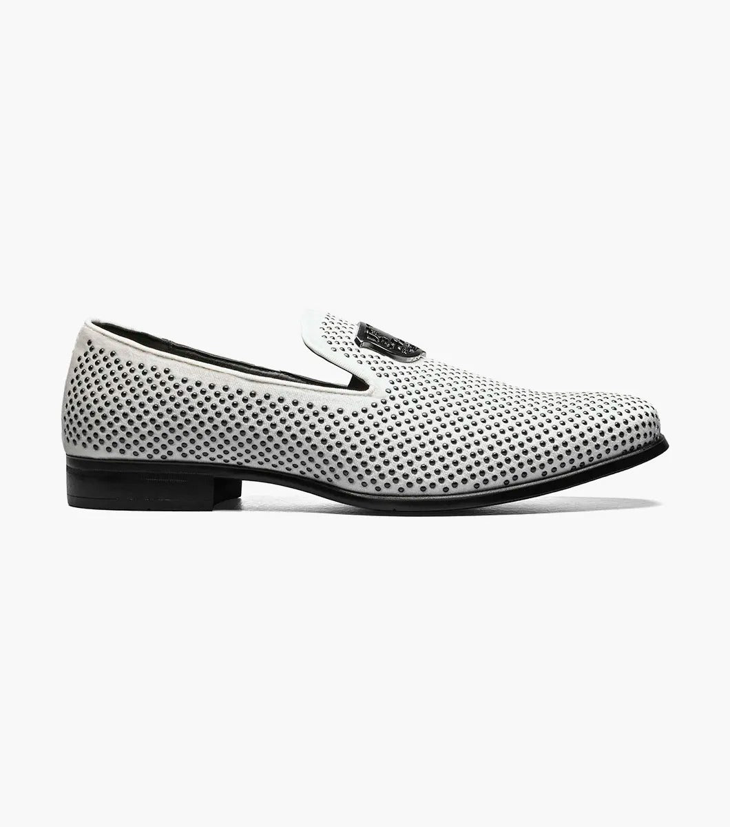 The Stacy Adams - SWAGGER Studded Slip On (Black with White, 25228-111) showcases a striking design with a white studded leather loafer contrasted by a black sole and adorned with a decorative metal emblem on top, offering both style and comfort thanks to its Memory Foam insole.