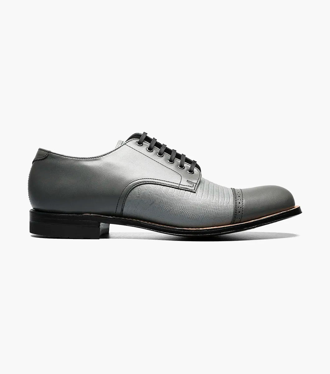 Introducing the Stacy Adams MADISON Lizard Cap Toe Oxford in Steel Gray, a sophisticated leather lace-up dress shoe from STACY ADAMS, meticulously designed with kidskin leather and featuring a detailed cap toe and a sleek black sole.