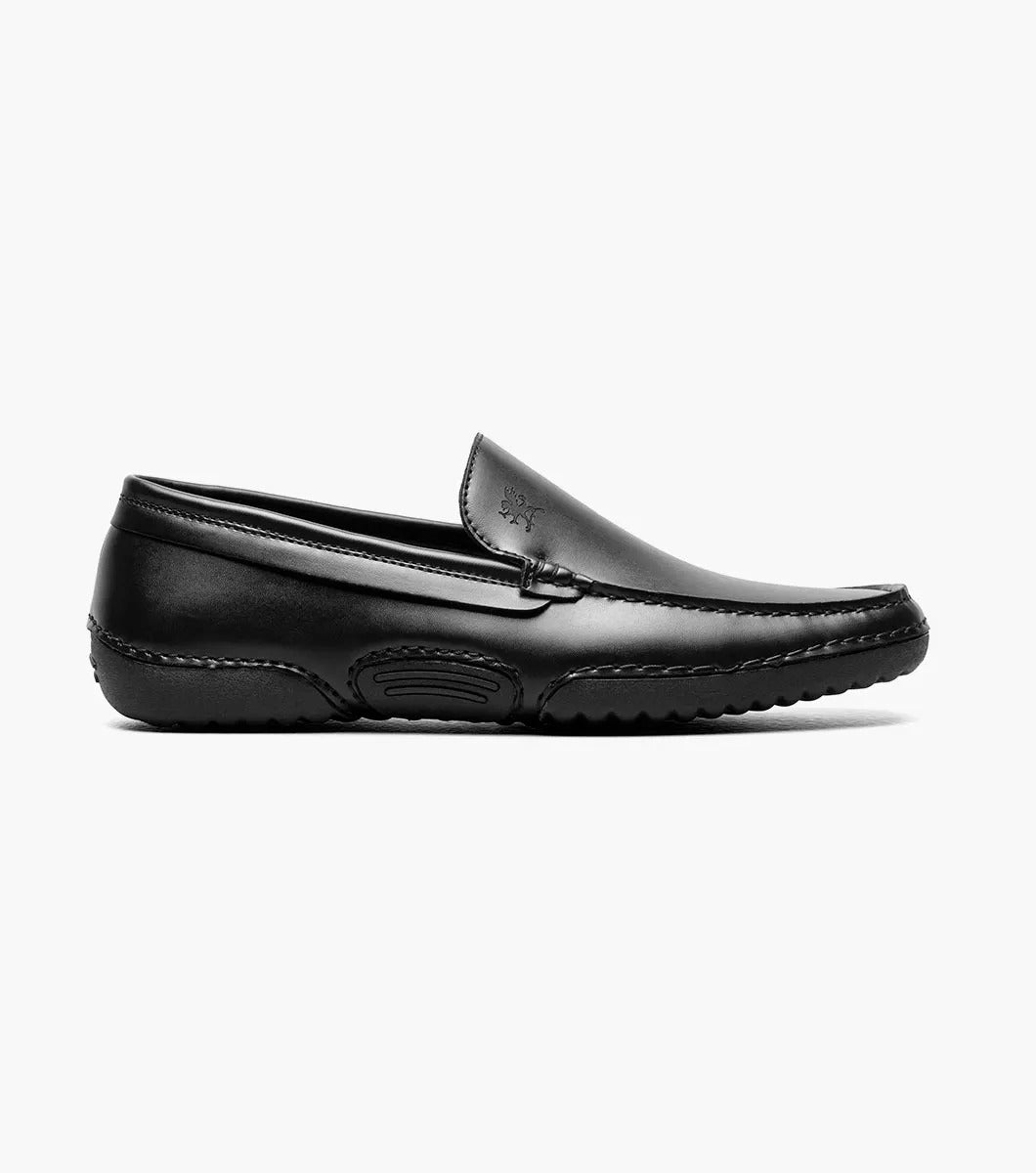 A Stacy Adams DEL Moc Toe Loafer in black leather, featuring a discreet logo on the side. The interior is lined with a striped pattern, providing both style and comfort.