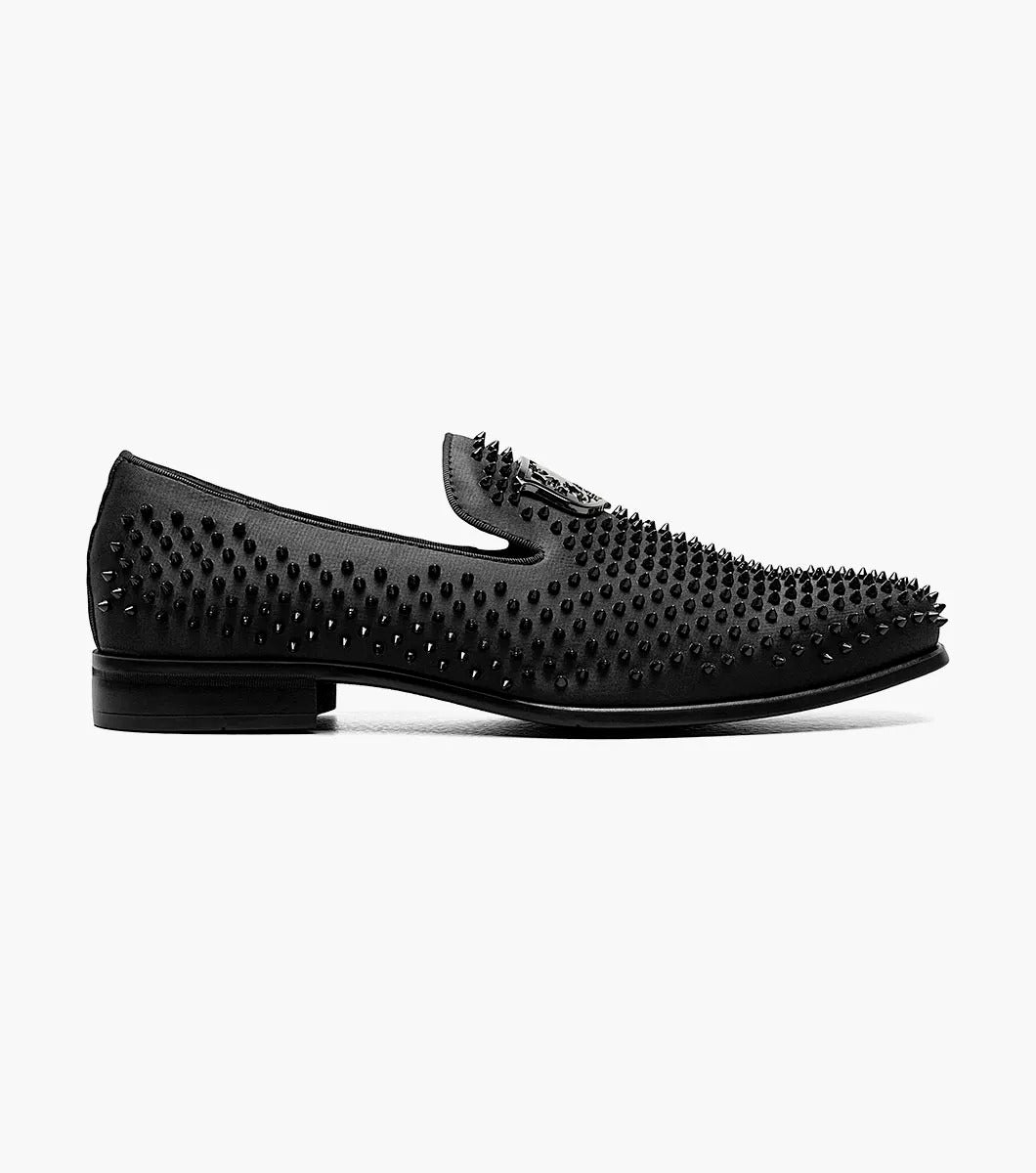 The Stacy Adams SABRE Spiked Slip On (21528-001) boasts a black studded design with a shiny emblem on the upper. Enhanced with Memory Foam, this stylish shoe from STACY ADAMS delivers both flair and comfort, all set against a pristine white background.