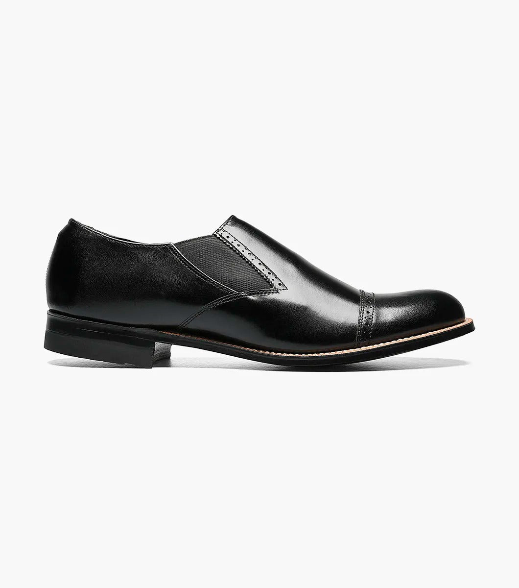 Introducing the Stacy Adams - MADISON Cap Toe Slip On, a sleek black kidskin leather dress shoe with a cap toe design and elastic side panels, presented against a white backdrop.